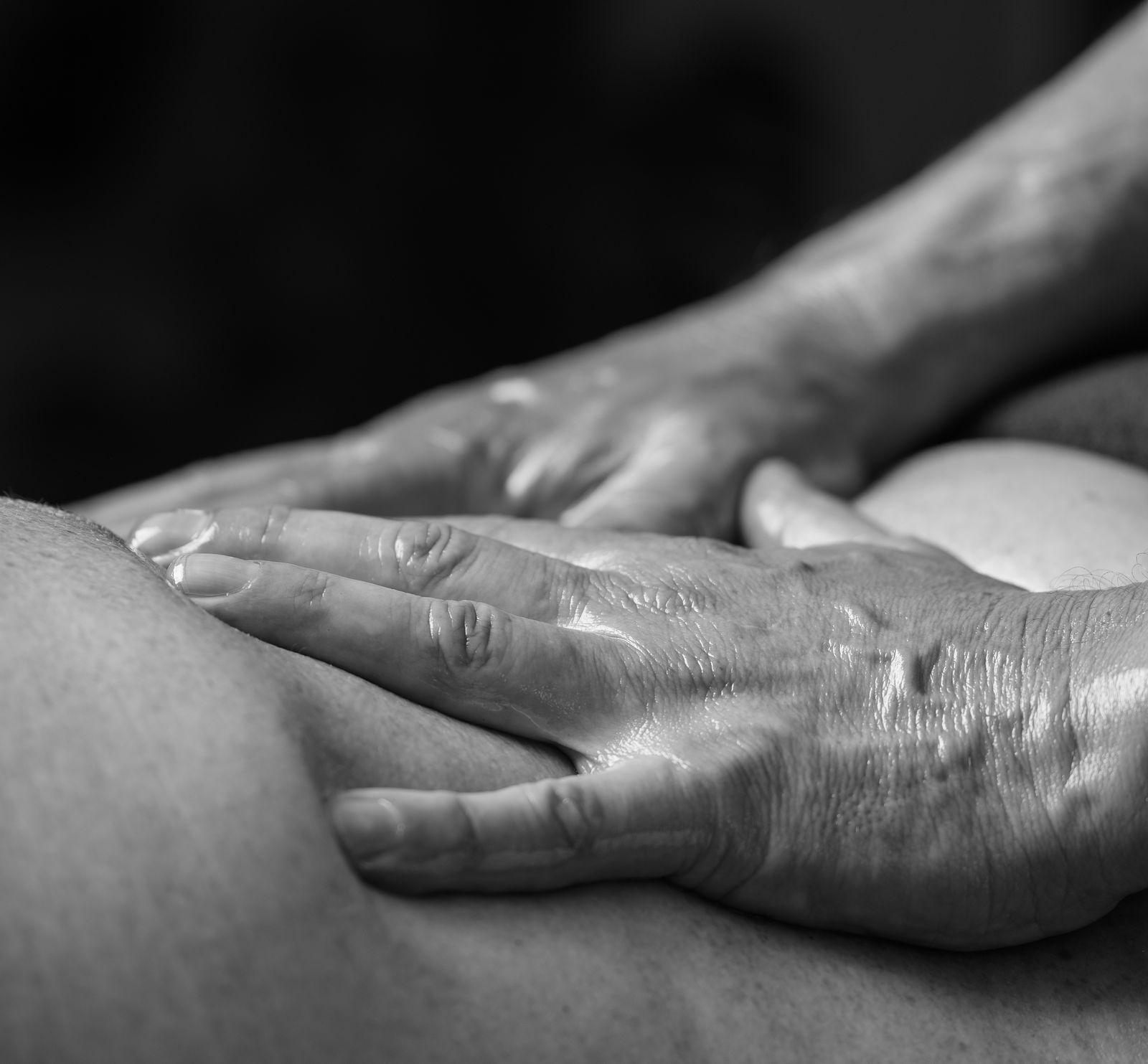 Handen van massagetherapeut Hans Mol tijdens een behandeling, in zwart-wit